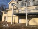 View of the home's backyard with an elevated deck and siding in need of repair at 5657 E Fall Creek Pkwy N Dr, Indianapolis, IN 46226