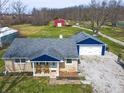 Charming home with a stone exterior, blue trim, a detached garage, and rocking chairs on the front porch at 7212 E Rocklane Rd, Needham, IN 46162