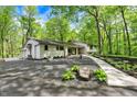 Scenic home featuring a sprawling gravel driveway framed by mature trees, lush greenery, and rock gardens at 8990 Pickwick Dr, Indianapolis, IN 46260
