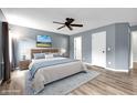Comfortable main bedroom featuring an expansive bed, wood flooring, a ceiling fan, and a stylish blue rug at 11124 Deer Valley Dr, Indianapolis, IN 46229