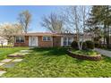 Classic brick ranch-style home featuring a well-maintained lawn, brick planter, and a walkway to the entrance at 1665 South Dr, Columbus, IN 47203