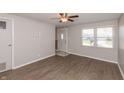 Bright living room with wood-look flooring, neutral walls, a ceiling fan, and a view of the front yard at 1665 South Dr, Columbus, IN 47203