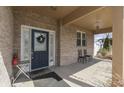 Inviting covered brick front porch with a decorative front door, welcome mat, and cozy seating area at 34 David Ln, Indianapolis, IN 46227