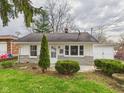 Single-story home with a well-maintained lawn, mature shrubs, and an attached garage at 612 Woodlawn Dr, Anderson, IN 46012