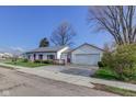 View of single-story home with a detached garage, fenced yard, and a metal roof at 102 E Thompson St, Lebanon, IN 46052