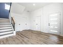 Bright foyer with wood-look flooring, stairs with iron railing, and contemporary white doors, offering a welcoming space at 1026 St Peter St, Indianapolis, IN 46203
