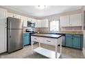 Kitchen with stainless steel appliances, an island, white upper cabinets, and colored lower cabinets at 1337 Linden St, Indianapolis, IN 46203