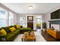 Staged living room with a green couch, fireplace, and an open doorway leading to another room at 1337 Linden St, Indianapolis, IN 46203