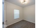 Simple bedroom featuring modern light fixture, plank flooring, and a bright window at 4363 Rhapsody Ln, Indianapolis, IN 46235
