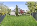 Spacious backyard with lush green lawn, mature trees, and a view of the home's exterior at 7259 Josiah Ct, Indianapolis, IN 46259