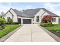 Beautiful white brick home with a three-car garage, lush landscaping, and a curved driveway in a suburban setting at 7259 Josiah Ct, Indianapolis, IN 46259