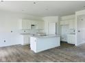 Kitchen features white cabinets, an island with a sink, and light countertops with wood-look floors. Ready for appliances! at 905 Saddlebrook Farms Blvd, Whiteland, IN 46184