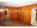 Cozy living room with rich wood paneling and hardwood floors leading to an arched doorway at 10327 Old National Rd, Indianapolis, IN 46231