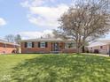 Brick home featuring a manicured front lawn and a shade tree at 1035 N Audubon Rd, Indianapolis, IN 46219