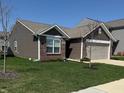 Exterior view of home with a manicured lawn, brick and siding, and two-car attached garage at 10869 Spirit Dr, Ingalls, IN 46048