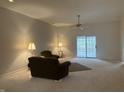 Large living room with neutral carpeting, ceiling fan, and sliding glass door to patio at 10949 Harness Way, Indianapolis, IN 46239