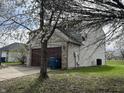 Side view of home with an attached garage, featuring brick and siding with a tree in bloom at 11147 Autumn Creek Ct, Indianapolis, IN 46229