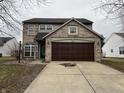 Front exterior of a brick and vinyl two-story home with a two-car garage and a well-manicured lawn at 11147 Autumn Creek Ct, Indianapolis, IN 46229