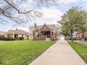 This well-maintained home has a long driveway leading to a detached garage, complemented by a lush green lawn at 1139 N Butler Ave, Indianapolis, IN 46219