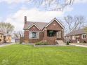 Charming brick home featuring a well-manicured lawn, landscaped garden beds, and a cozy covered front porch at 1139 N Butler Ave, Indianapolis, IN 46219