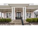 Inviting front porch featuring classic columns, hanging lanterns, and comfortable rocking chairs at 12813 Chapel Square St, Carmel, IN 46032