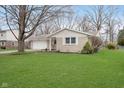A single-story home with a brick facade, attached garage, and a green lawn with landscaping at 1313 Roseway Dr, Indianapolis, IN 46219
