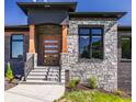 Stunning entryway features a modern door with stone and brick accents, set against a blue sky at 2428 S Morgantown Rd, Greenwood, IN 46143