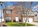 Two-story brick home featuring an attached two-car garage, landscaped yard, and a classic architectural design at 2468 Wyndham S Pl, Columbus, IN 47203