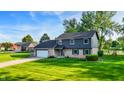 Charming two-story home with a brick and vinyl exterior, a well-manicured lawn, and a basketball hoop in the driveway at 3771 Lakewood Dr, Greenfield, IN 46140