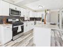 Modern kitchen featuring white cabinets, stainless steel appliances, and stylish backsplash, ideal for cooking enthusiasts at 3913 Eastern Dr, Anderson, IN 46012