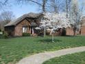 Beautiful brick home with lush green lawn and mature trees with blossoms in a desirable neighborhood at 6712 Forrest Commons Blvd, Indianapolis, IN 46227