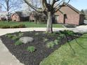 Well-maintained front yard with lush landscaping and a glimpse of the brick home behind the trees at 6712 Forrest Commons Blvd, Indianapolis, IN 46227