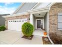 Close-up of the home's entrance highlighting the brick facade, dark front door, and neat landscaping around the porch at 7574 Merrick Dr, Brownsburg, IN 46112