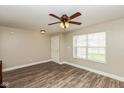 Bright living room featuring wood-look flooring, a ceiling fan, and a window offering natural light at 1167 Dark Star Ct, New Whiteland, IN 46184