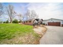 A spacious house and garage are accompanied by a cozy seating area outside the back at 16371 State Road 38 E, Noblesville, IN 46060