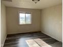Vacant bedroom with wood-look flooring, a gray rug, and a window view at 635 Laclede St, Indianapolis, IN 46241