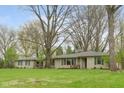 A home featuring a stone facade, green shutters, and a sprawling front yard under large trees at 7575 Holliday W Dr, Indianapolis, IN 46260
