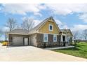 Side exterior view with a three car garage and beautiful brick and vinyl siding details under a clear blue sky at 10151 E 191St St, Noblesville, IN 46060