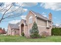 A two-story brick home with a side-entry garage sits on a lush green lawn with mature landscaping at 10157 Woods Edge Dr, Fishers, IN 46037