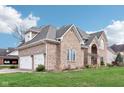 A two-story brick home boasts a three-car garage, mature landscaping, and lush green lawn at 10157 Woods Edge Dr, Fishers, IN 46037