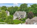 Aerial view of brick home with well-manicured lawn, mature trees, and a two car garage at 11974 Volcanic Rock Dr, Fishers, IN 46037