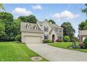 Charming brick home with an attached garage, lush landscaping, and a long driveway at 11974 Volcanic Rock Dr, Fishers, IN 46037