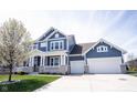 Stylish home featuring a covered front porch, a two-car garage, concrete driveway, blue siding, and tidy landscaping at 14918 Dawnhaven Dr, Westfield, IN 46074