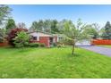 A well-manicured lawn features a lovely brick home and mature landscaping, offering excellent curb appeal at 2910 S Sheridan Ave, Indianapolis, IN 46203