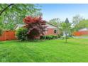 Green lawn with mature trees create a serene setting for the charming single-story brick home at 2910 S Sheridan Ave, Indianapolis, IN 46203