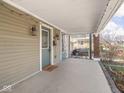 Inviting covered porch with quaint lighting, a brick foundation and green door at 317 E 37Th St, Indianapolis, IN 46205