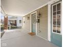Cozy covered porch with stylish lanterns, a brick foundation and green front door at 317 E 37Th St, Indianapolis, IN 46205