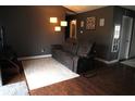 Cozy living room featuring hardwood floors, a leather sofa with side tables, and a modern floor lamp at 401 Paddlebrook Dr, Danville, IN 46122