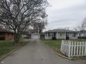 Street view showcasing a light-colored single-story home with a detached garage and a long driveway at 406 W Jackson St, Alexandria, IN 46001