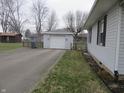 Detached one-car garage with white siding and a single door, adjacent to a paved driveway and lawn at 406 W Jackson St, Alexandria, IN 46001